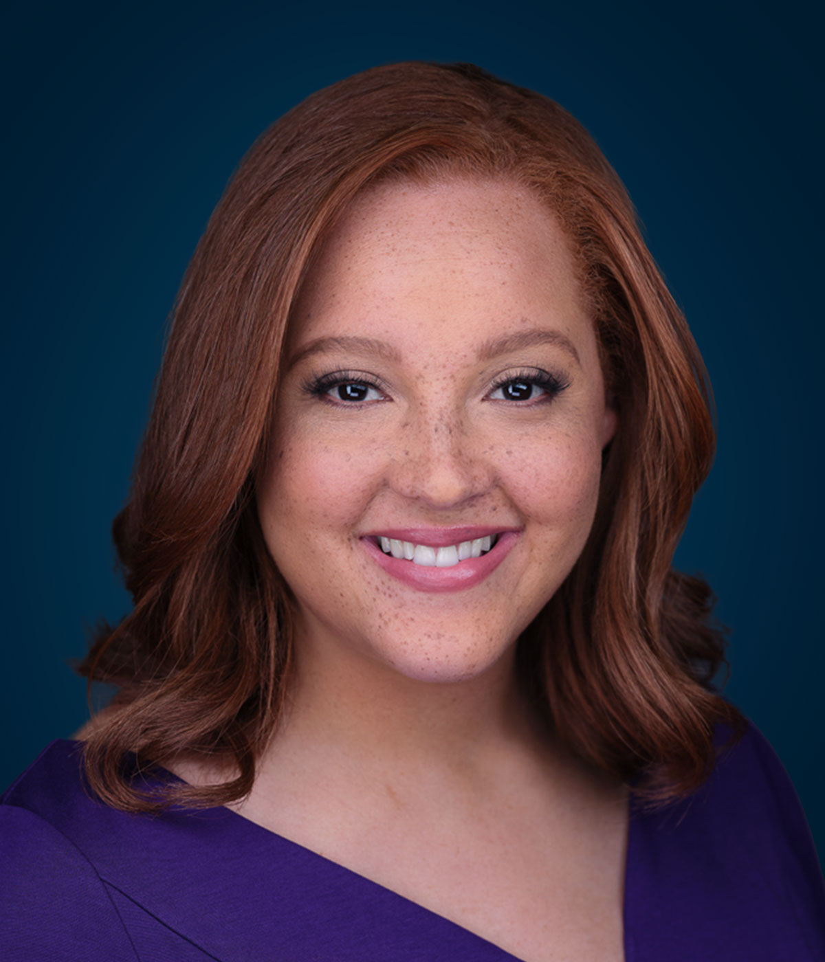 a woman wearing a purple shirt and smiling at the camera